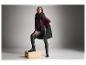 Model in zwart gewatteerd vest, bordeaux trui en leren broek.