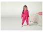 Een meisje draagt een roze onesie met hartjes en lacht.