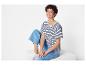 Een vrouw draagt een gestreepte t-shirt, blauwe jeans en witte sneakers.