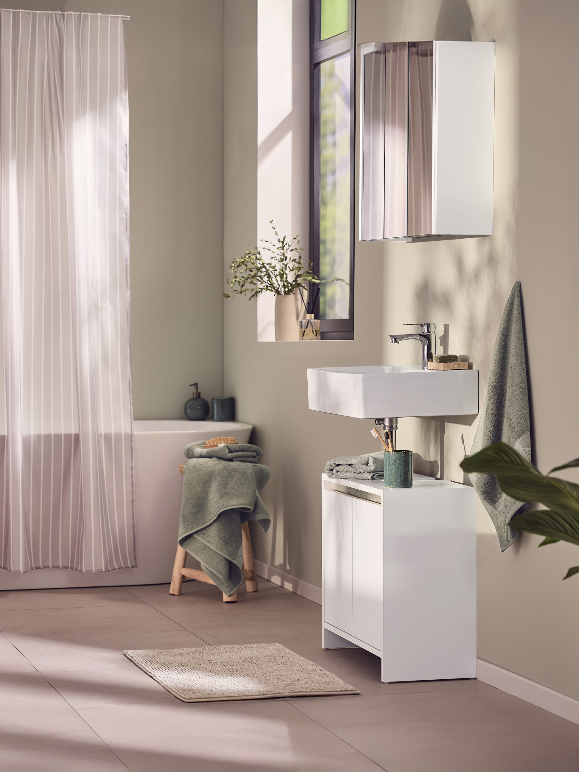 Salle de bain moderne avec lavabo blanc, meuble sous-vasque et rideau de douche rayé.