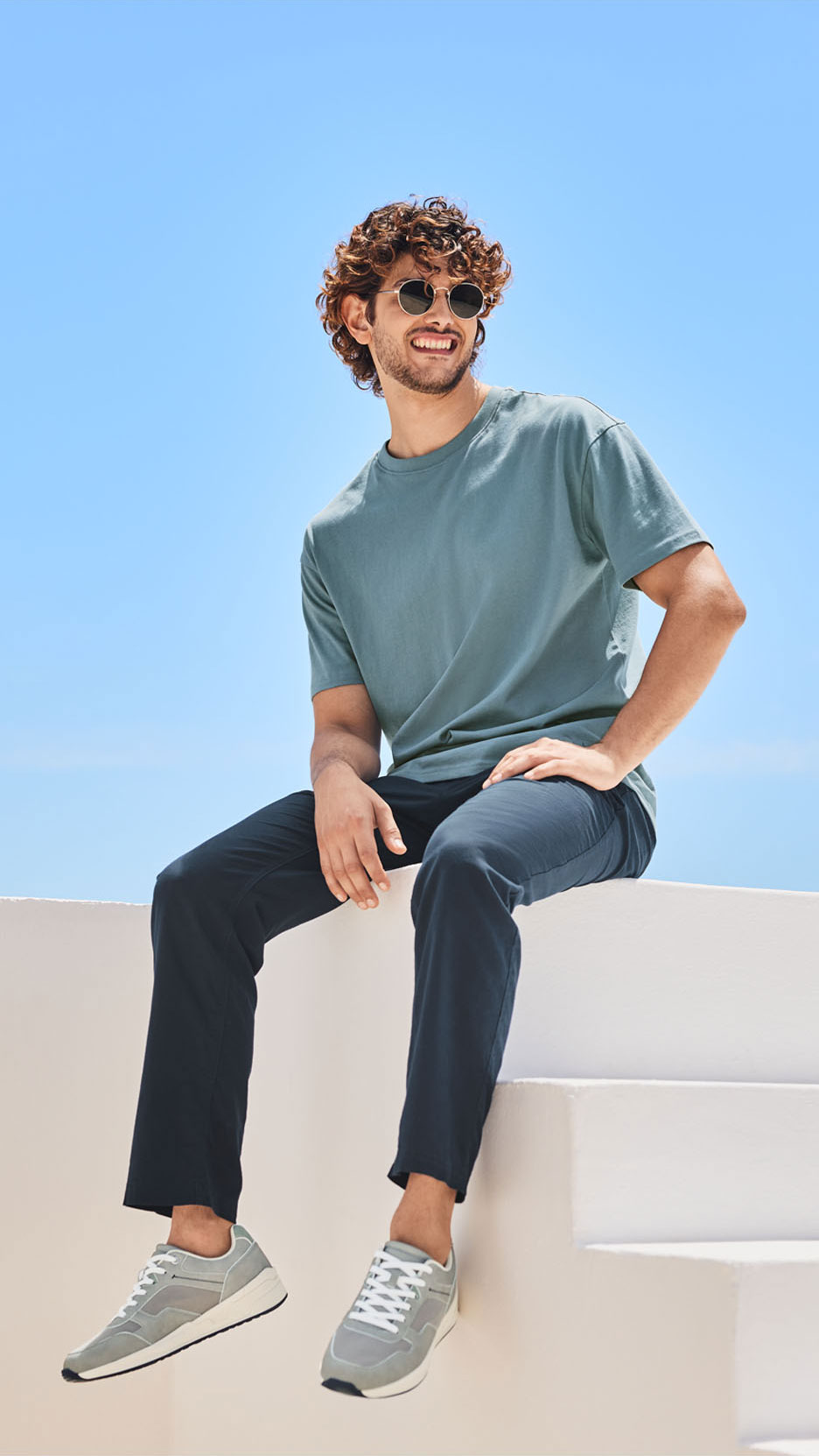 Man in lichtgroen t-shirt, donkerblauwe broek en grijze sneakers.