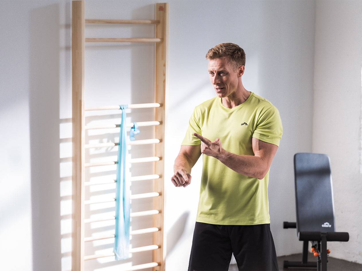Un homme en tenue de sport devant une espalier avec une bande de résistance.