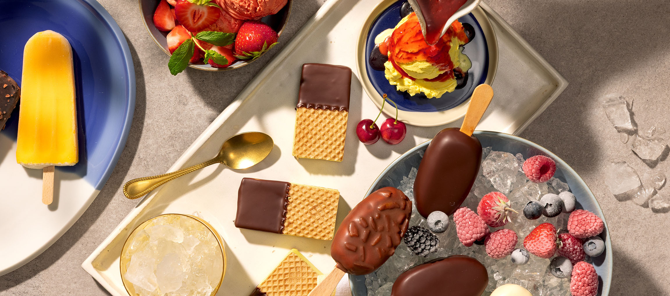Assortiment van ijslolly's, ijsschepjes en chocolade-gedoopte wafels met bessen.