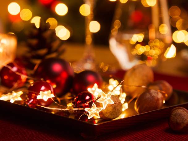 Kerstdecoraties met rode kerstballen, stervormige lichtjes en hazelnoten op een dienblad.