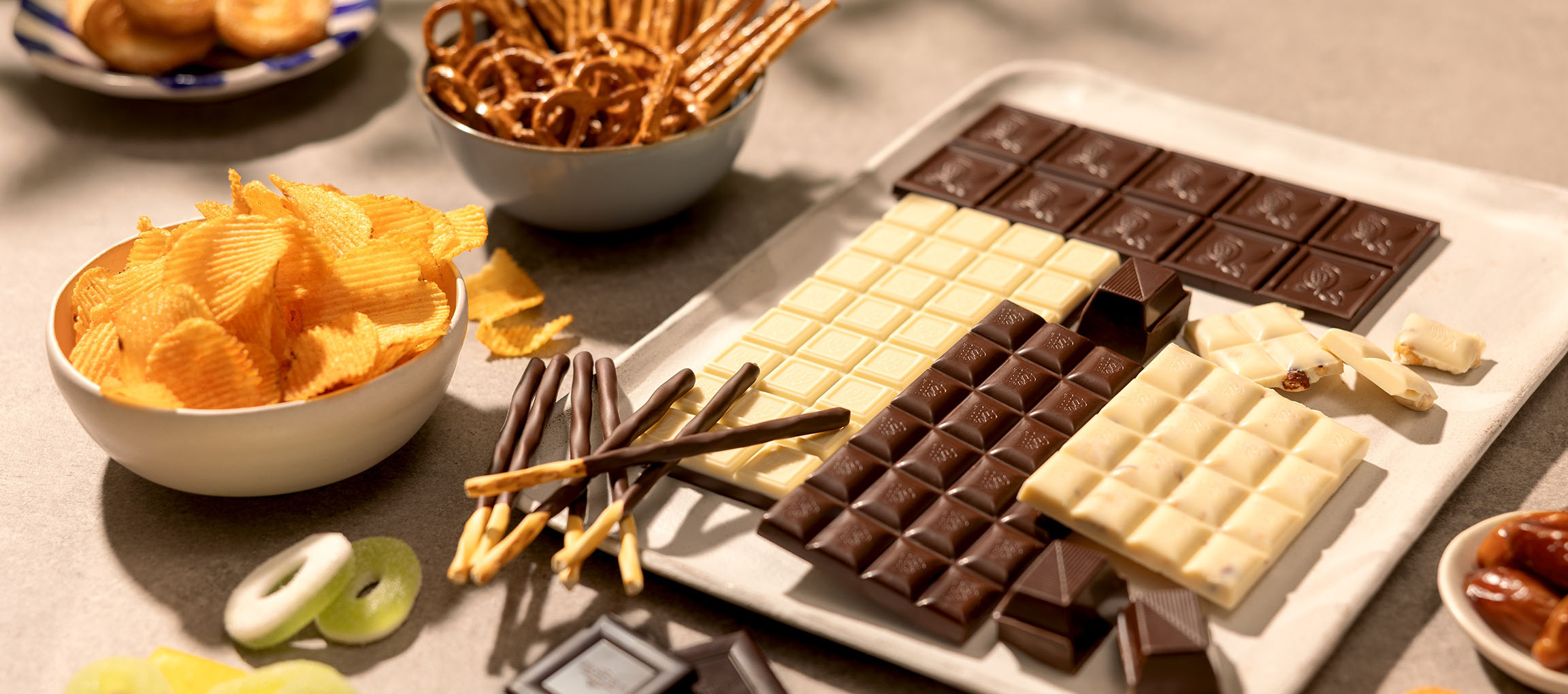 Assortiment de chocolats, chips, bretzels et bonbons sur une table.