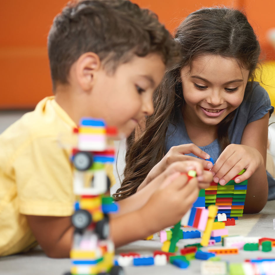 Twee kinderen spelen met kleurrijke bouwblokken op de vloer.
