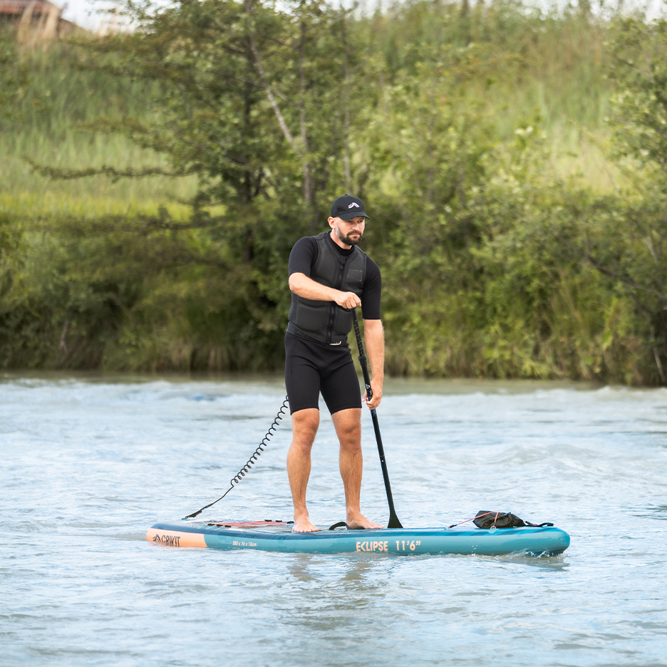 Man op Crivit Eclipse 11'6' paddleboard met zwemvest en peddel.