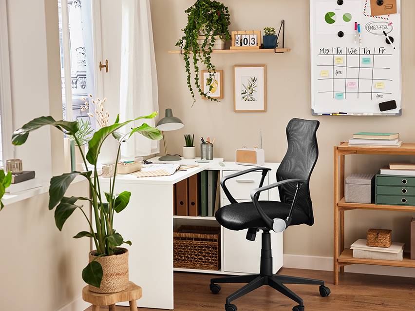 Een moderne thuiswerkplek met een zwarte mesh bureaustoel en een wit bureau.