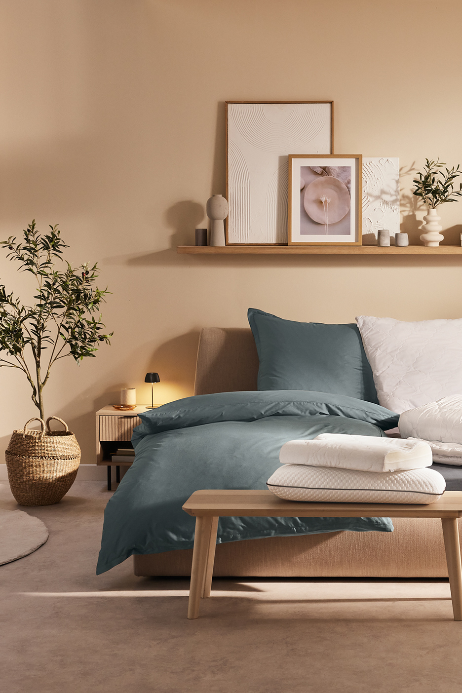 Moderne slaapkamer met blauwgroen beddengoed, witte kussens en een gedecoreerde plank.
