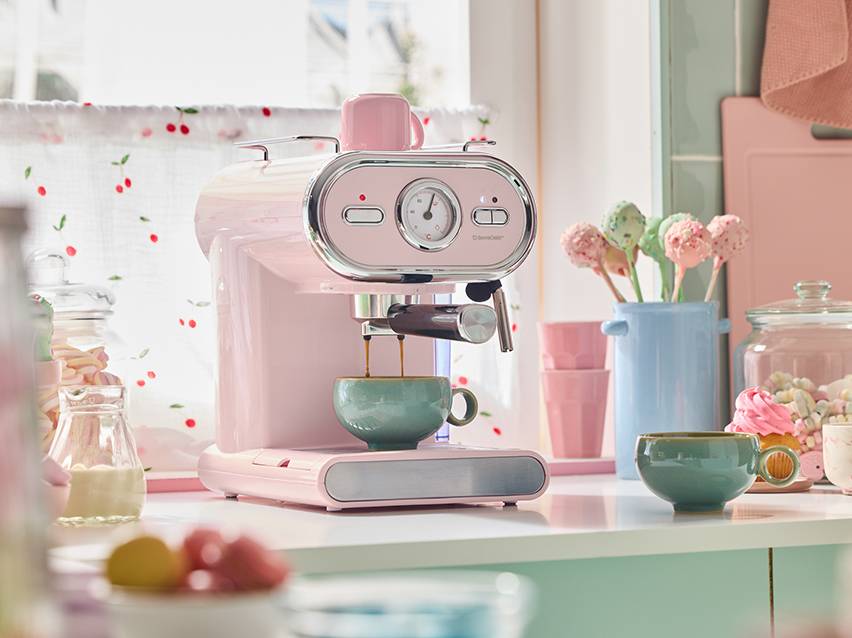Roze koffiezetapparaat in retrostijl dat koffie zet in een pastelkleurige keuken.