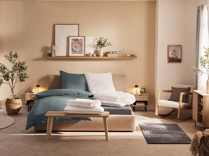 Moderne slaapkamer met bed, beddengoed, kussens en houten meubels.