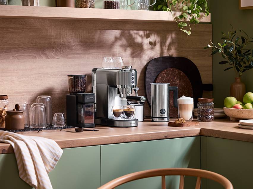 Espressomachine, koffiemolen en melkopschuimer op een houten aanrecht in de keuken.