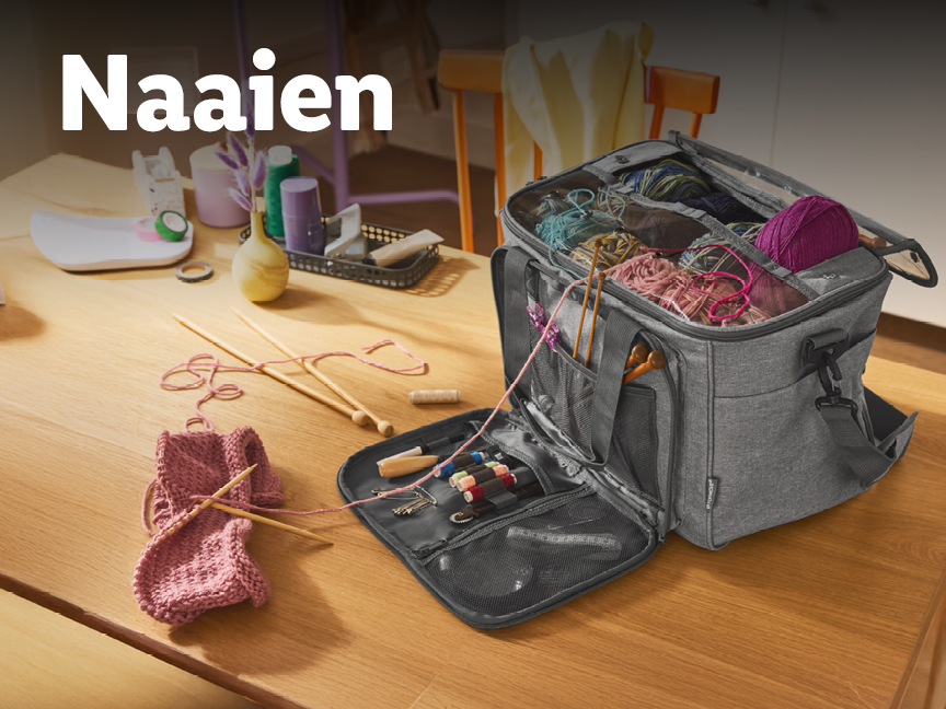 Een grijze tas met breigaren en naalden op een houten tafel.