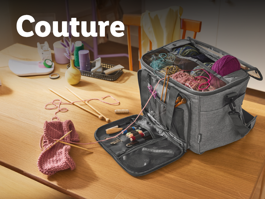 Un sac de couture gris rempli de pelotes de laine et d'aiguilles à tricoter sur une table en bois.