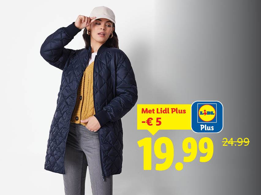 Een vrouw draagt een marineblauwe gewatteerde jas, een geel vest en een grijze spijkerbroek, met een beige pet.