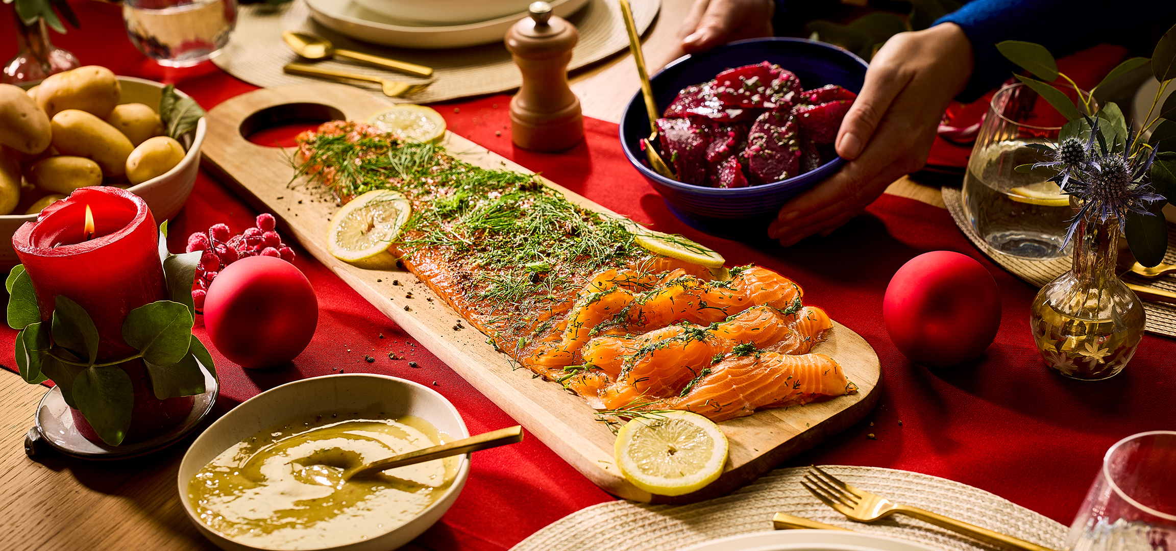 Gerookte zalm, aardappelen en bietensalade op een feestelijke rode tafel.