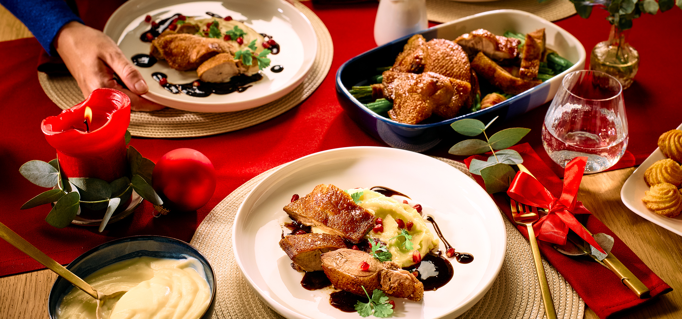 Kerstdiner met eend, aardappelpuree, granaatappel en een kommetje saus.