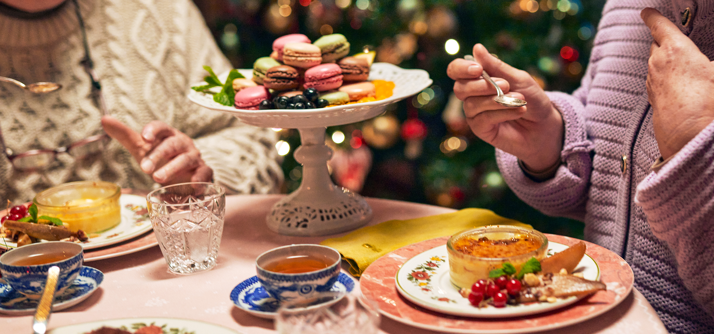 Kleurrijke macarons en fruit op een schaal, met mensen op de achtergrond.