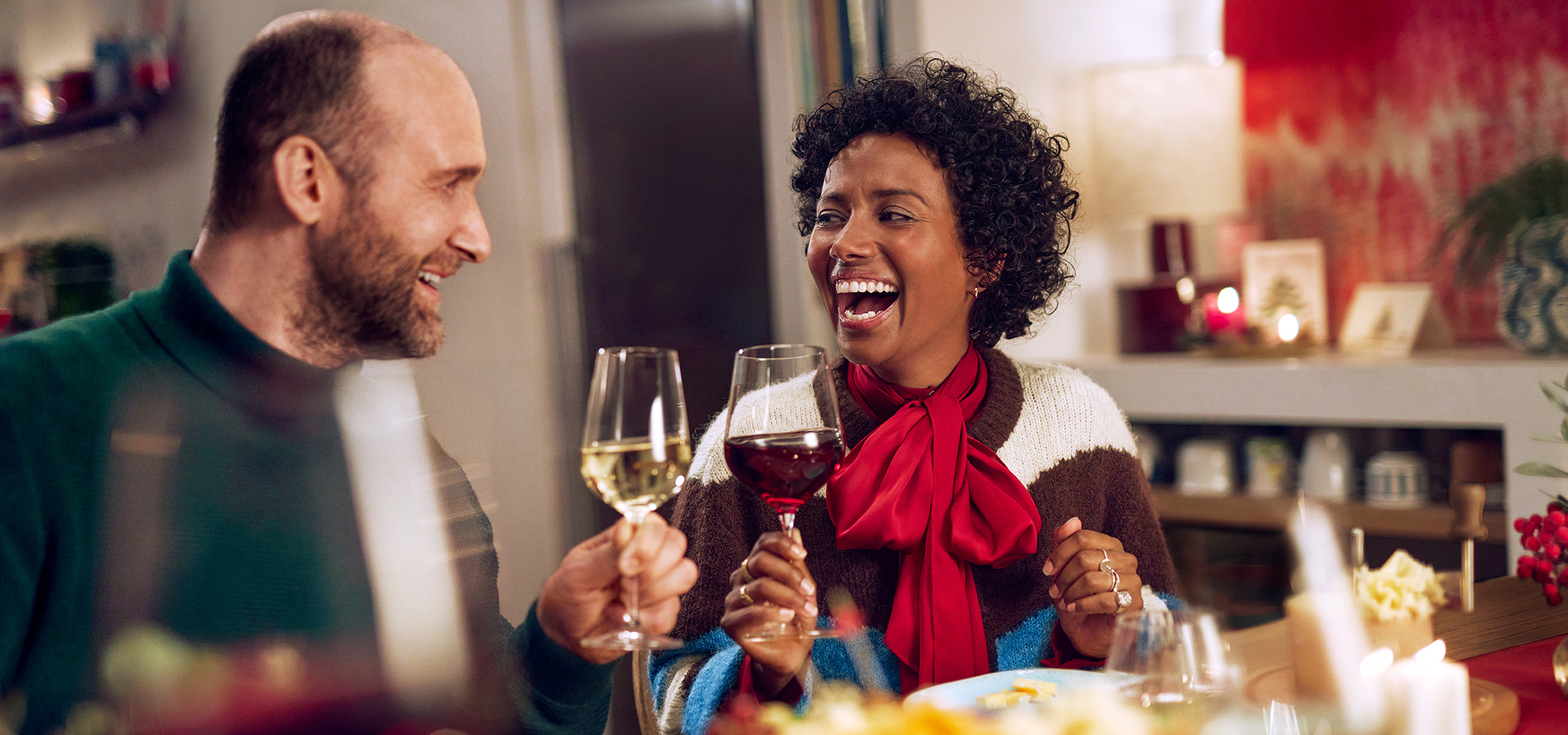 Een lachend stel toost met witte en rode wijn.