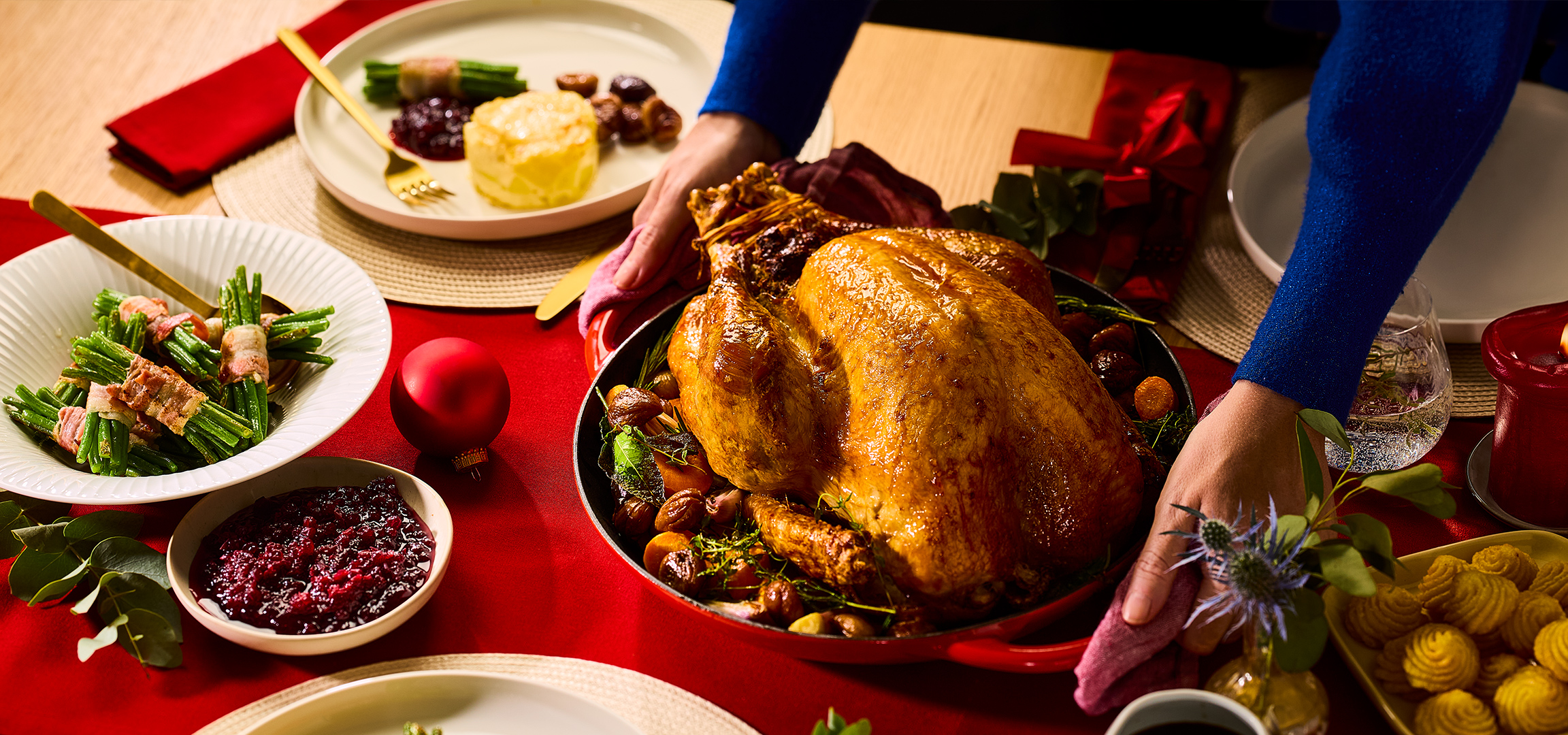 Geroosterde kalkoen en sperziebonen omwikkeld met spek op een rode kersttafel.