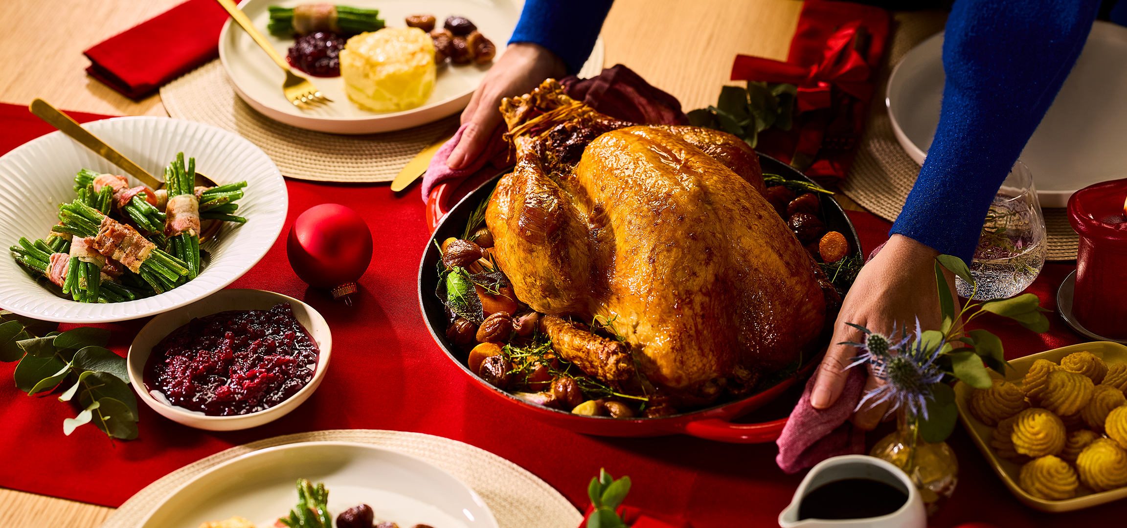 Feestelijk diner met gebraden kalkoen, sperziebonen met spek en cranberrysaus op een rode tafel.