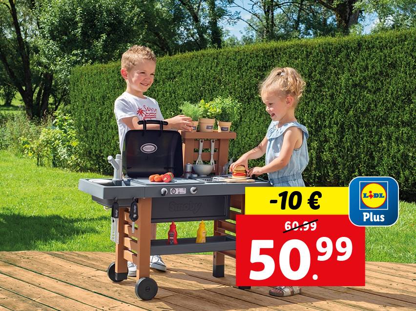 Deux enfants jouent avec une cuisine et un barbecue Smoby dans un jardin.
