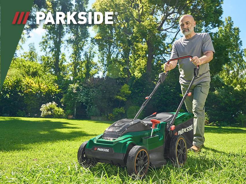 Een man maait het gazon met een Parkside grasmaaier in een zonnige tuin.