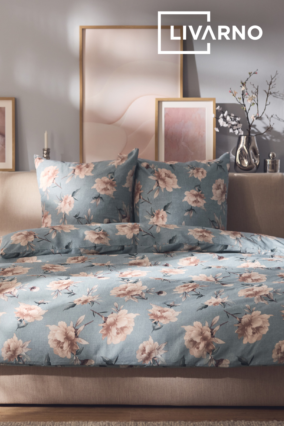 Beddengoed met bloemenprint in een slaapkamer met ingelijste kunst en decoratieve vazen.