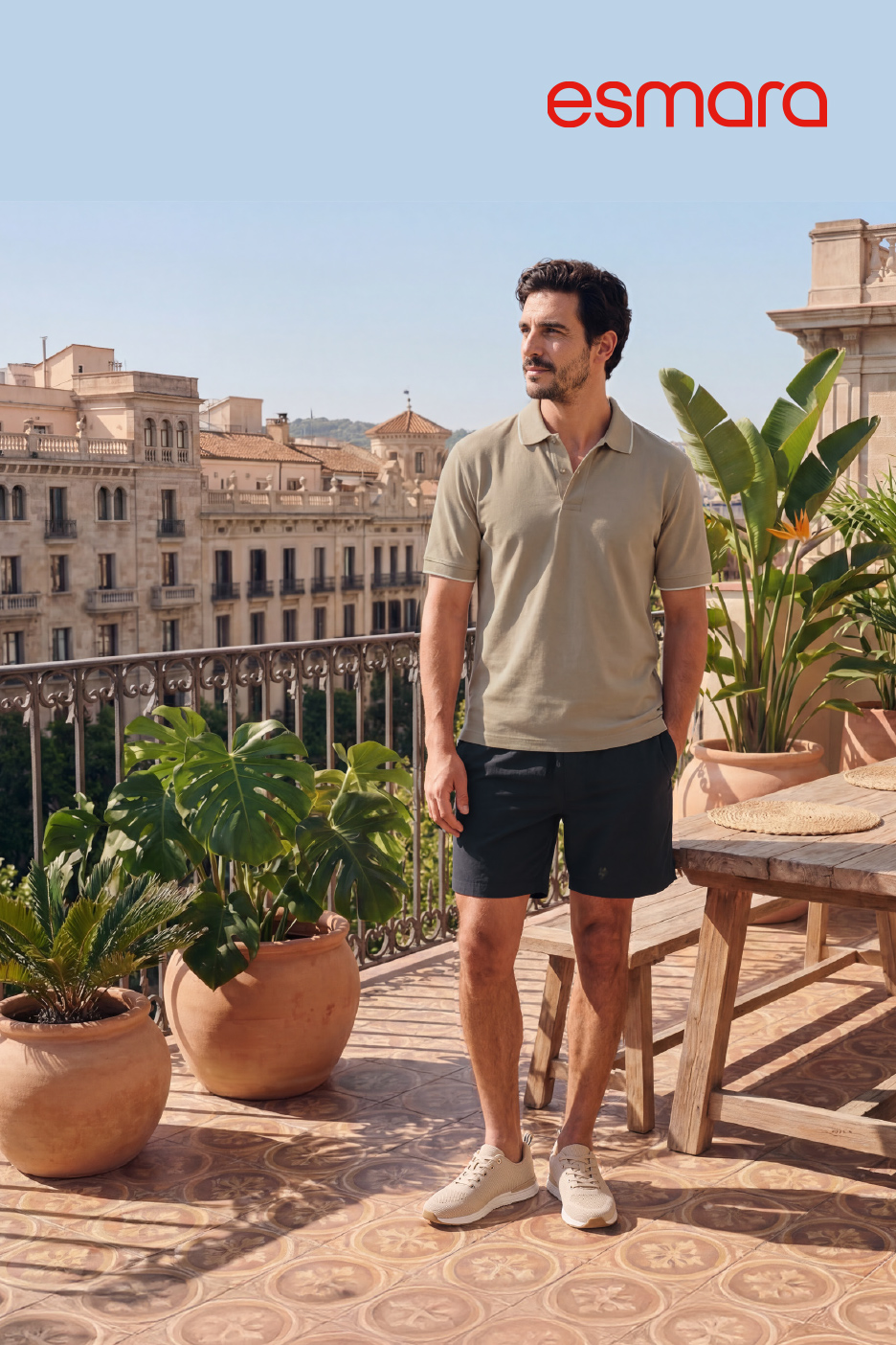 Man in poloshirt en korte broek op zonnig balkon met uitzicht op de stad.