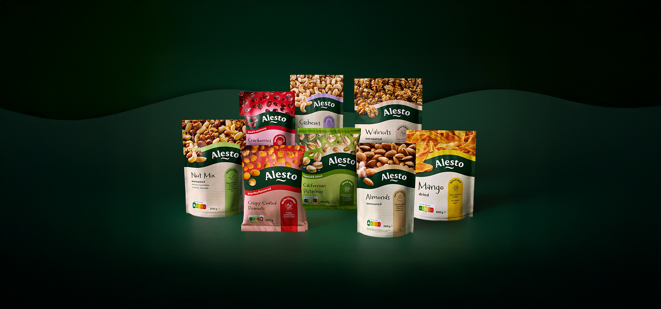 Un assortiment de noix et de fruits secs, incluant des noix de cajou, des noix, des canneberges et de la mangue, sur fond vert foncé.