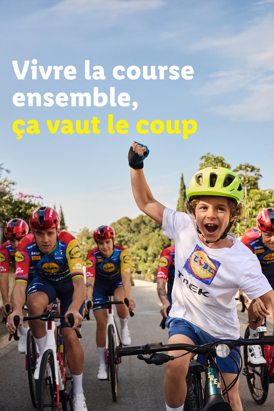 Een groep fietsers, waaronder een kind, fietst samen op een zonnige dag. Tekst: 'Samen de race beleven, dat is de moeite waard.'