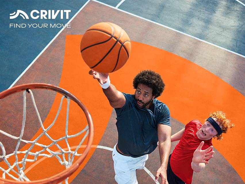 Twee mannen basketballen op een buitenveld, één staat op het punt te scoren.