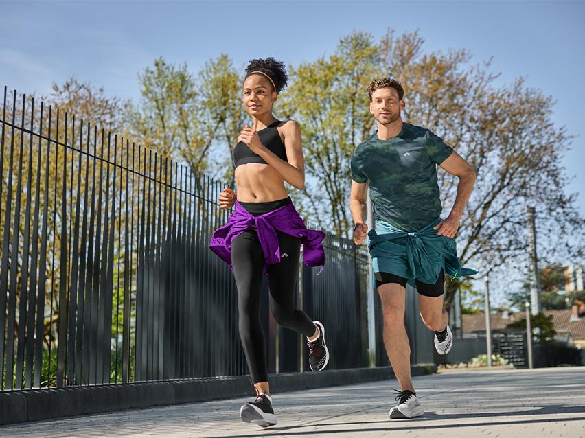 Twee sporters rennen buiten, gekleed in sportkleding en hardloopschoenen.