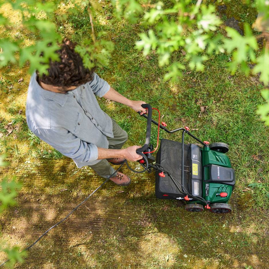 Homme tondant la pelouse avec une tondeuse électrique, vue d'en haut.