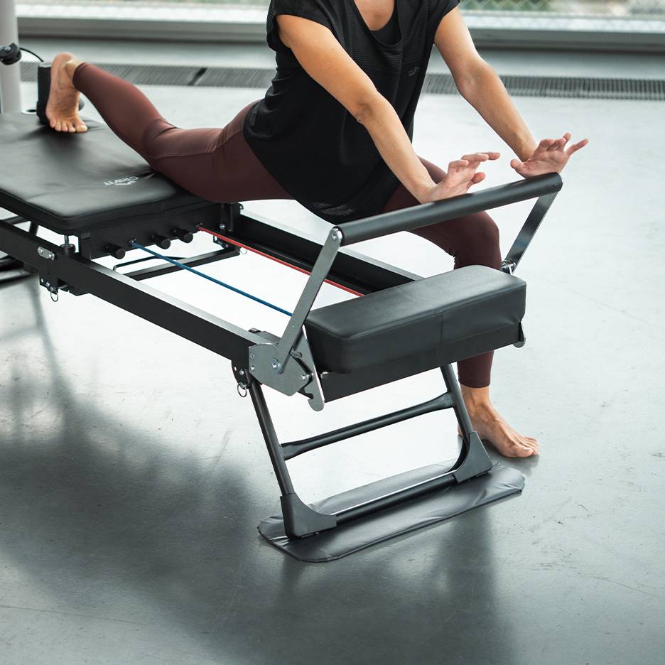 Vrouw traint op een Pilates-apparaat in sportkleding