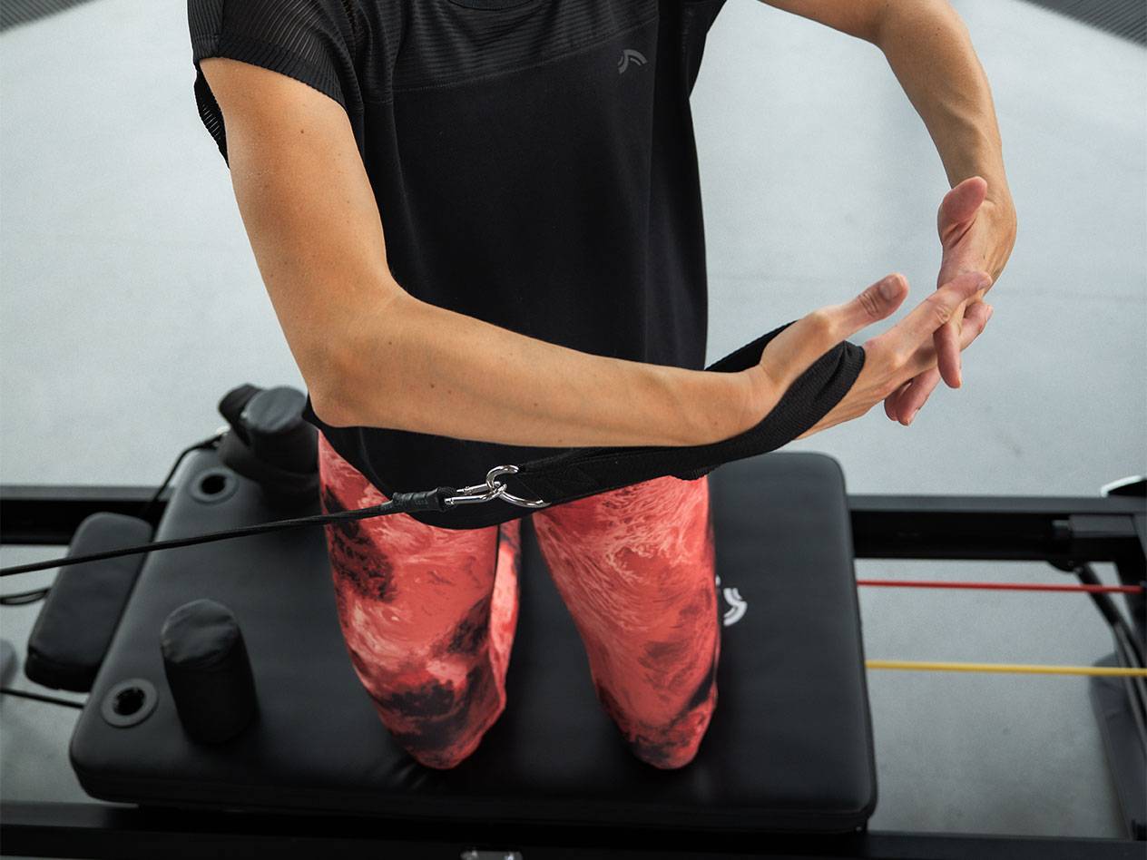 Vrouw traint met weerstandsbanden op een Pilates-apparaat.
