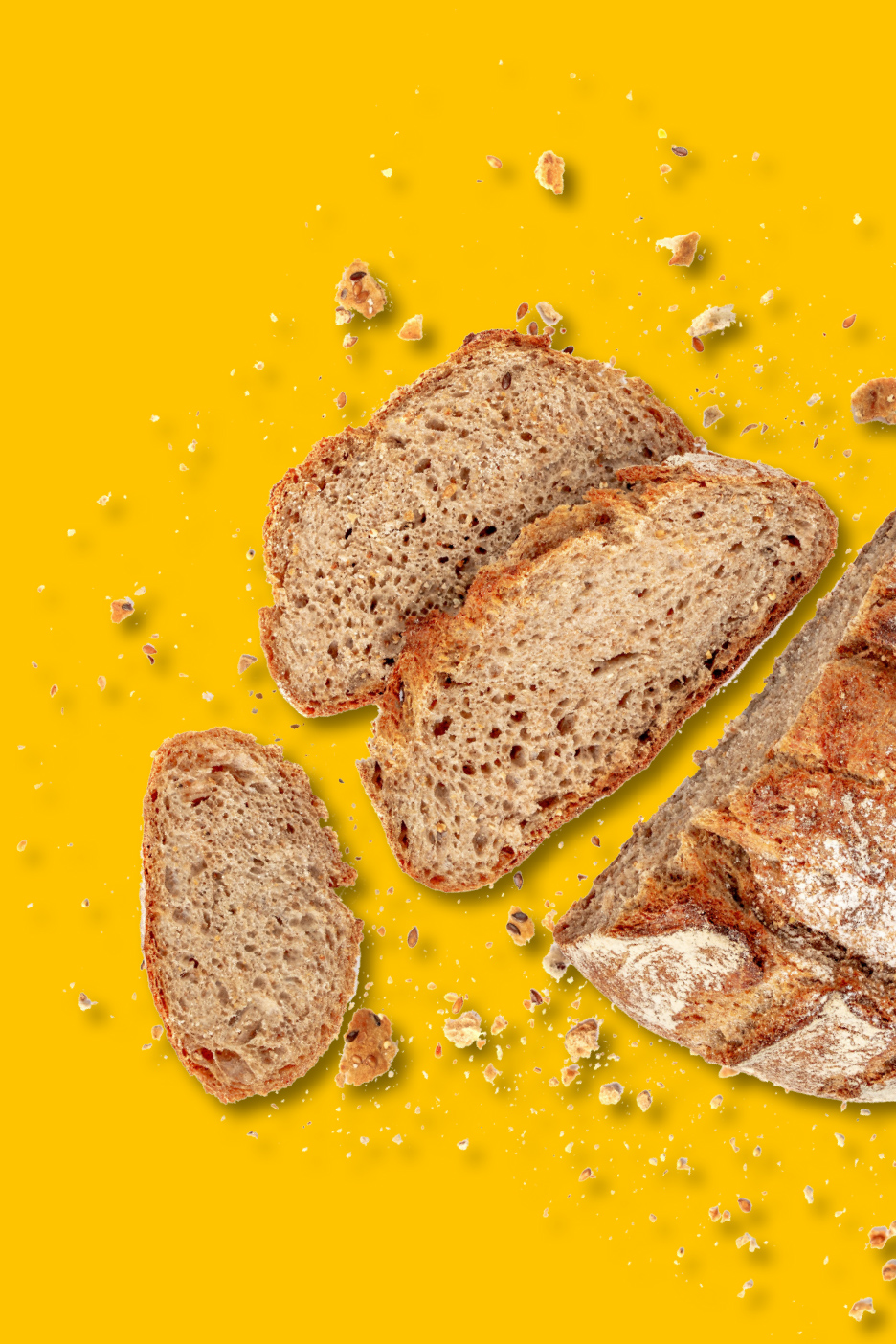 Plakjes roggebrood en kruimels op een gele achtergrond.