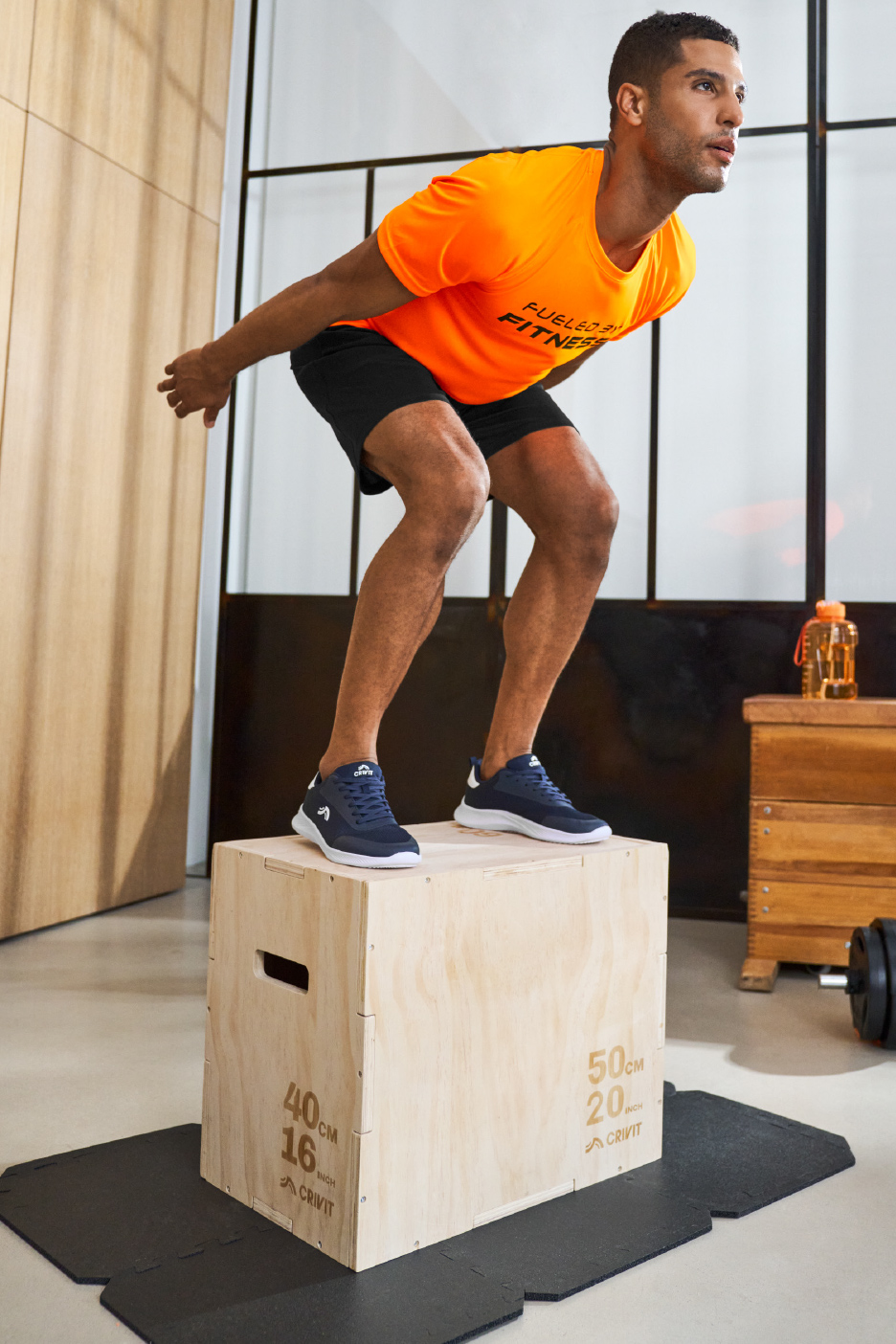 Man in Crivit sportkleding en sneakers op een plyobox.