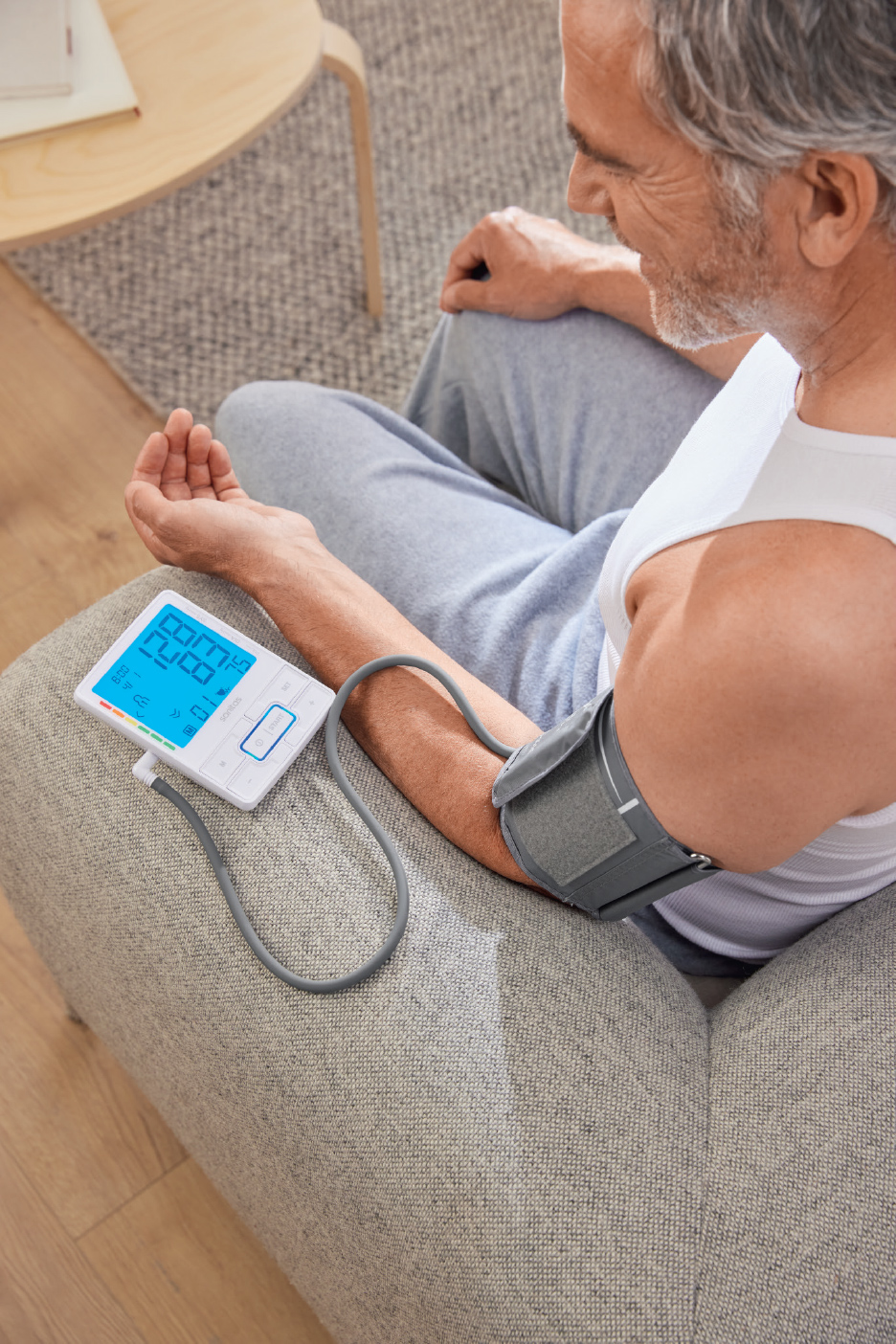 Man meet bloeddruk met een bloeddrukmeter, zittend op een bank.