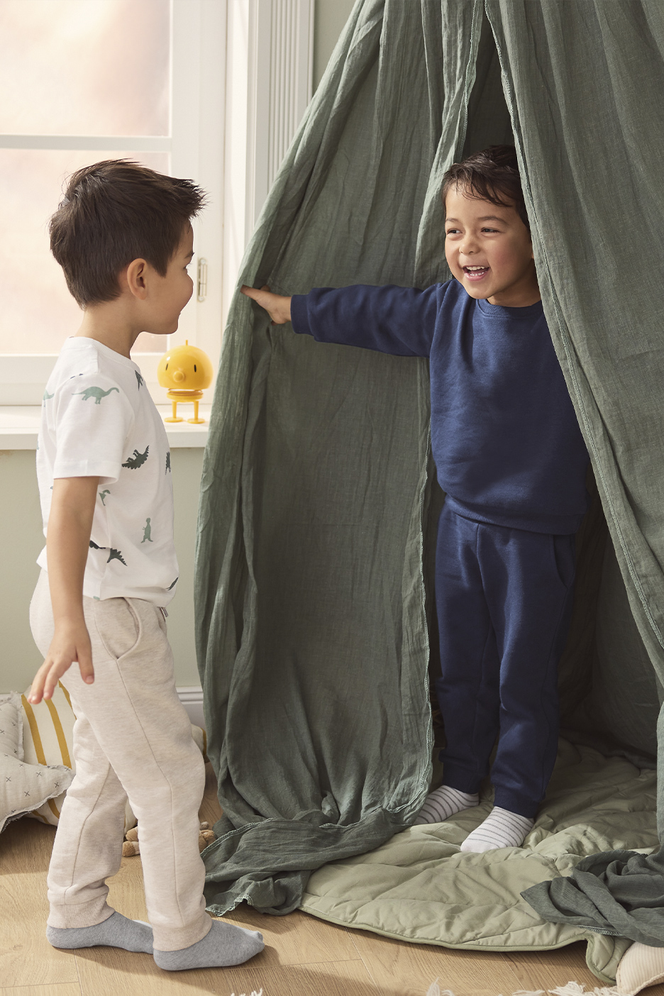 Twee jongens in comfortabele kleding spelen in een speelhut.