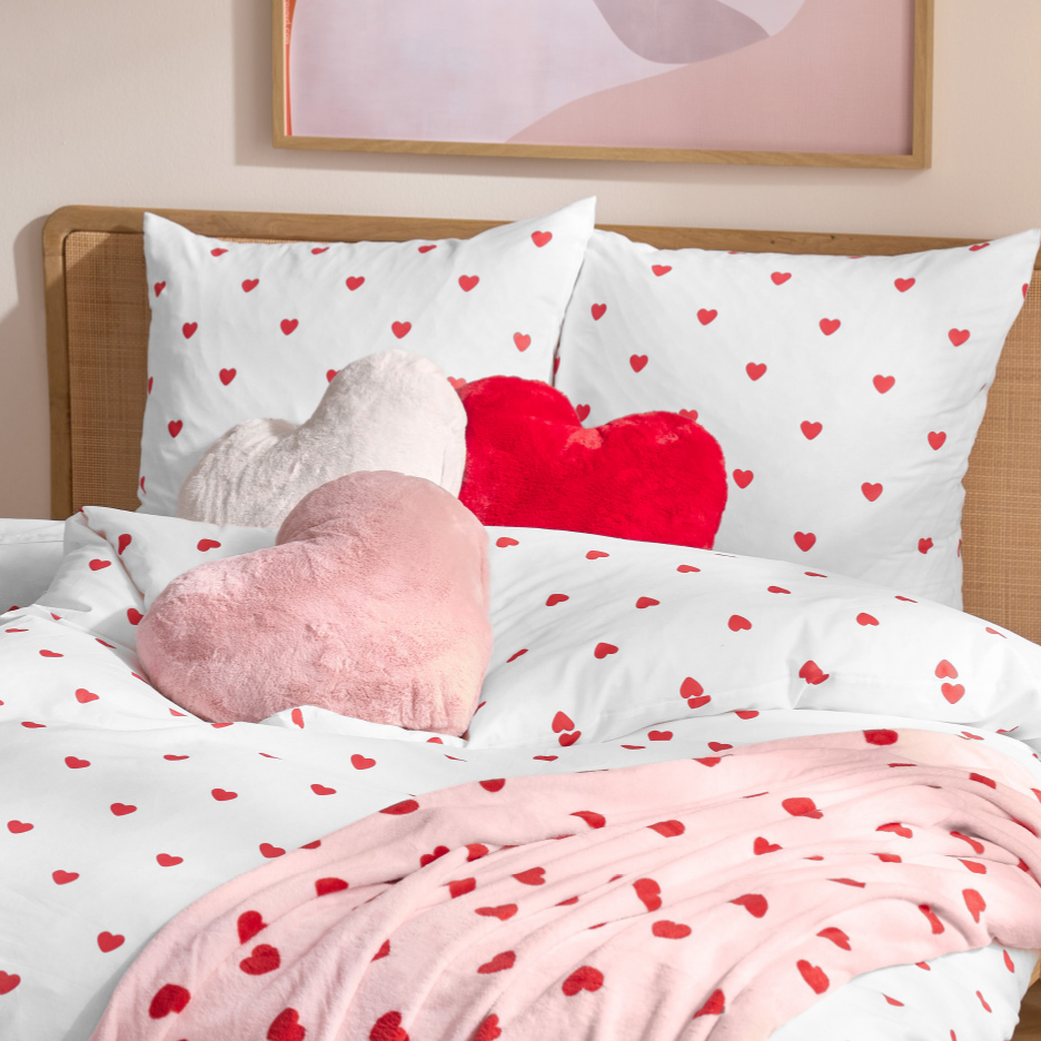 Beddengoed met hartjesprint en hartvormige kussens in rood, wit en roze.