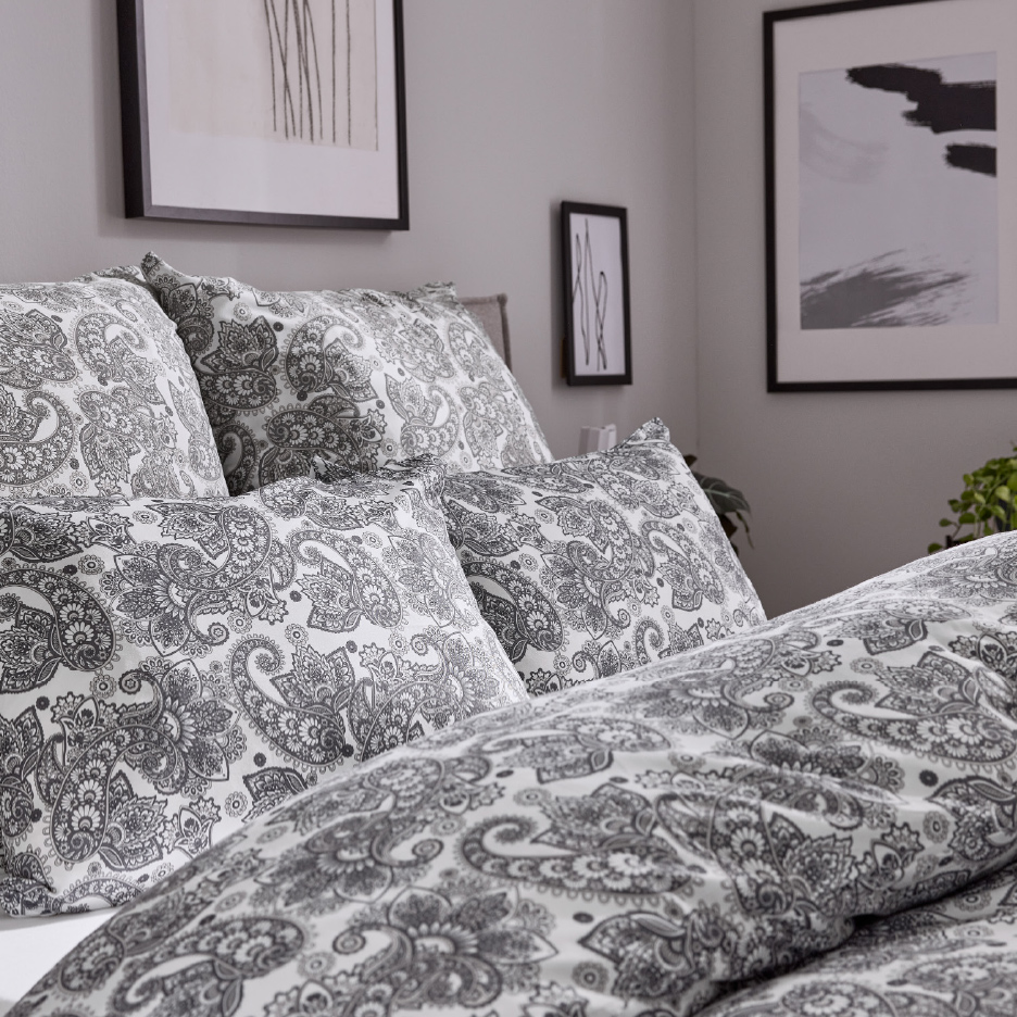 Grijs-wit paisley beddengoed op een bed in een moderne slaapkamer.