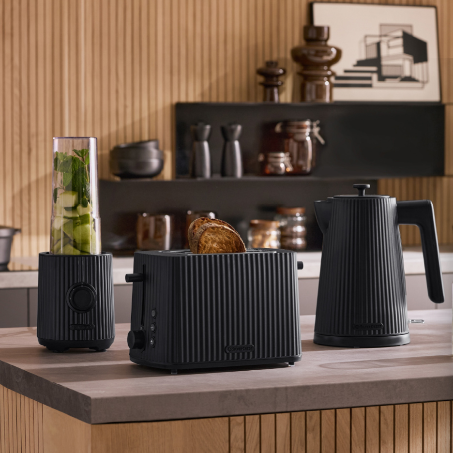 Een geribbelde zwarte broodrooster, waterkoker en blender op een houten aanrecht in de keuken.