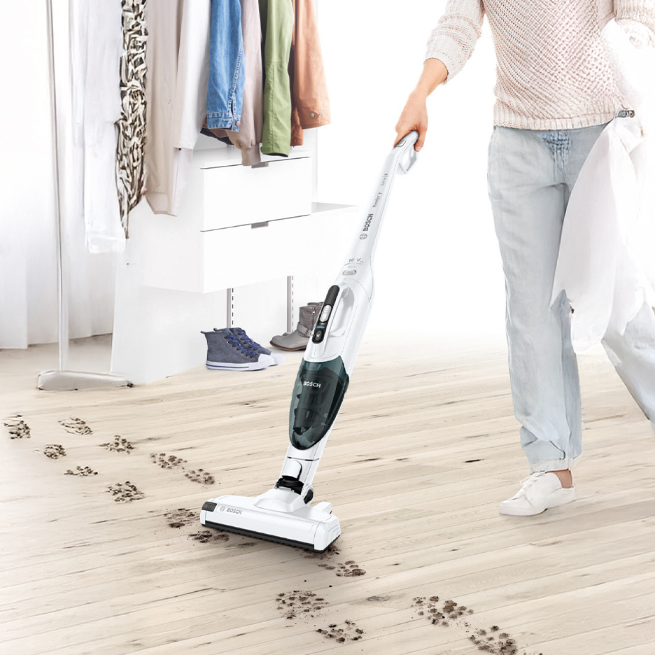 Draadloze steelstofzuiger verwijdert pootafdrukken van een lichte houten vloer.