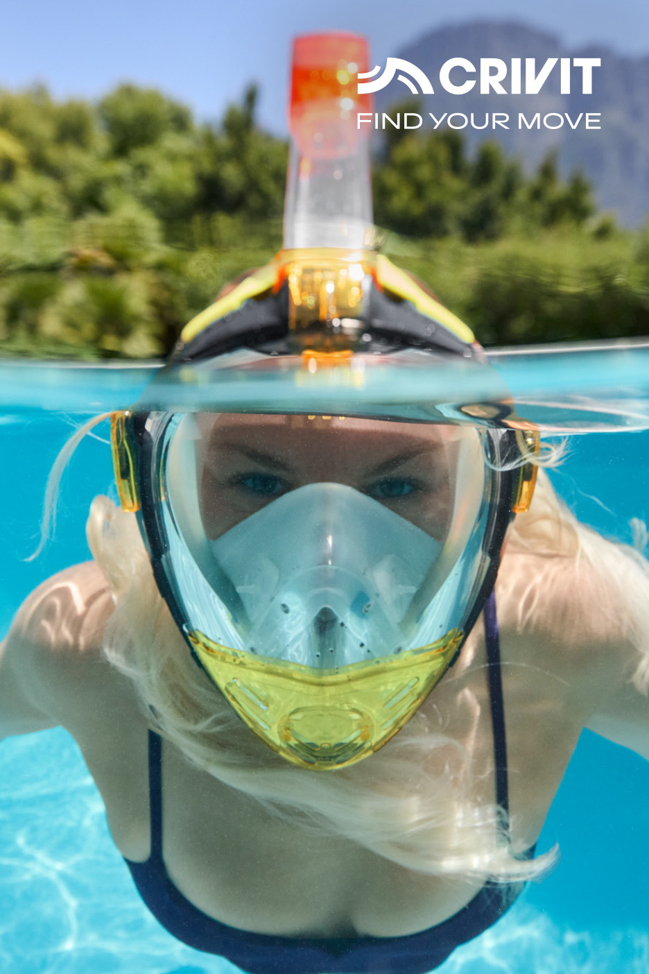 Vrouw met snorkelmasker zwemt in zwembad, bergen en bomen op de achtergrond.