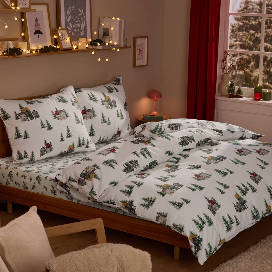 Slaapkamer met beddengoed met winterdorp-thema, lichtslingers en kerstdecoraties.