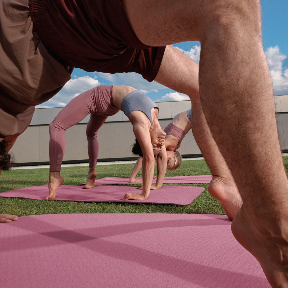 Mensen doen yoga buiten op yogamatten, gekleed in sportkleding.