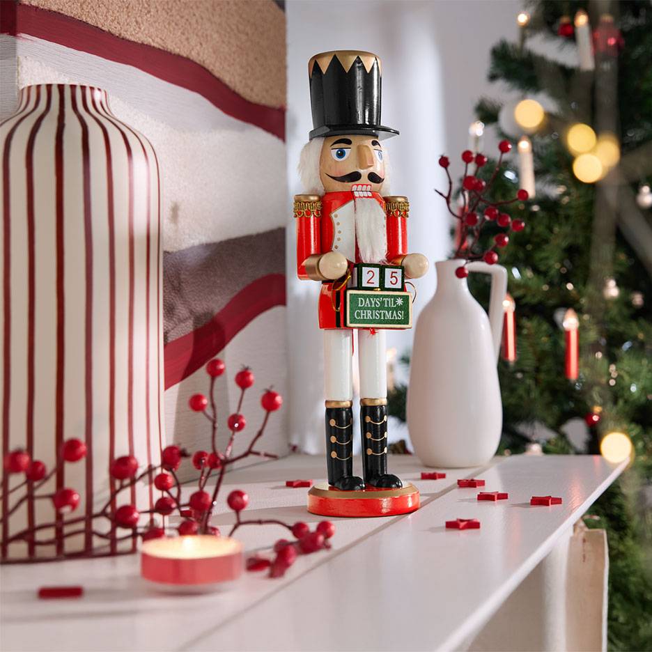 Notenkraker met adventskalender, vazen en kerstdecoraties op een plank.