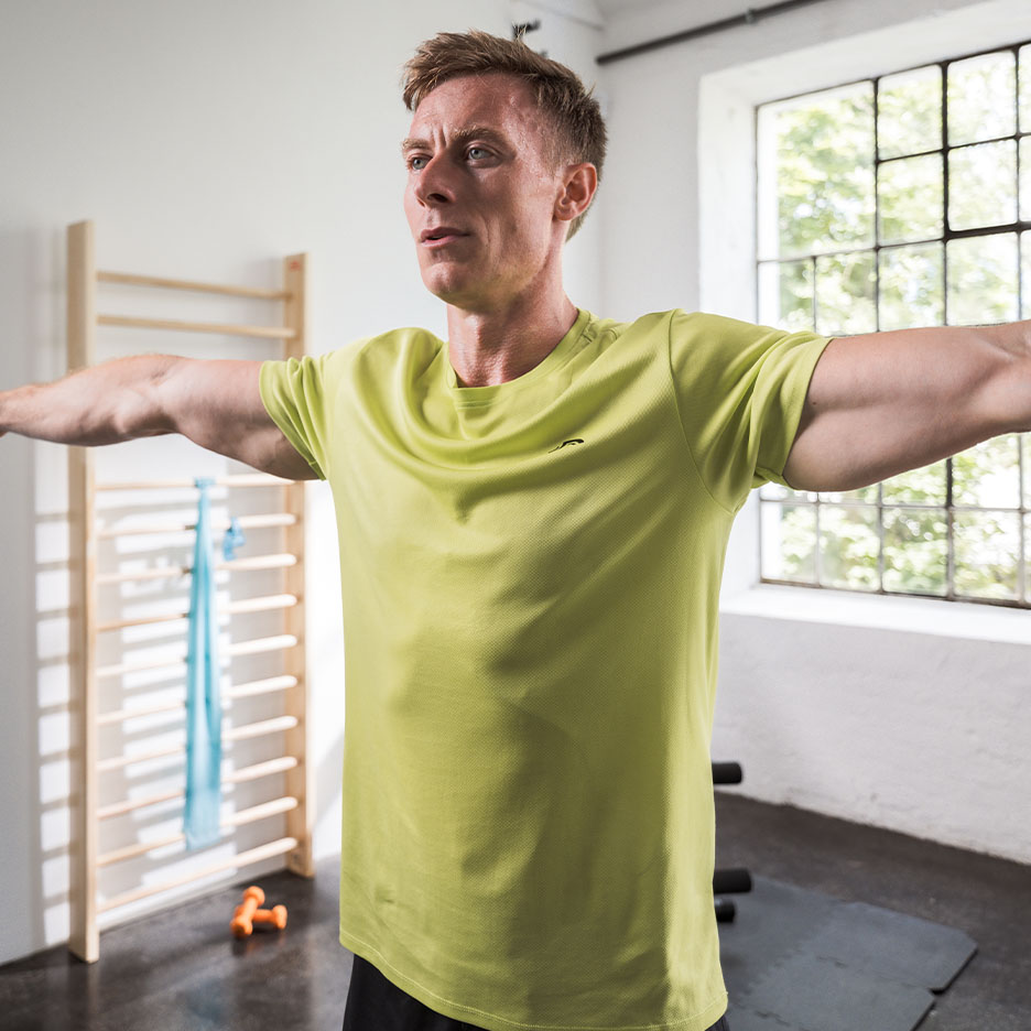 Man in groen sportshirt oefent in een sportschool.