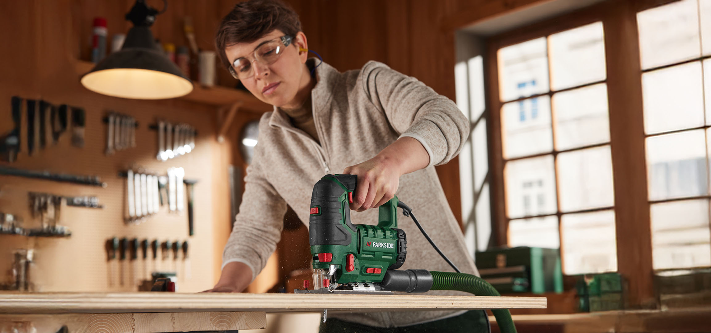 Vrouw gebruikt een Parkside decoupeerzaag om hout te zagen.